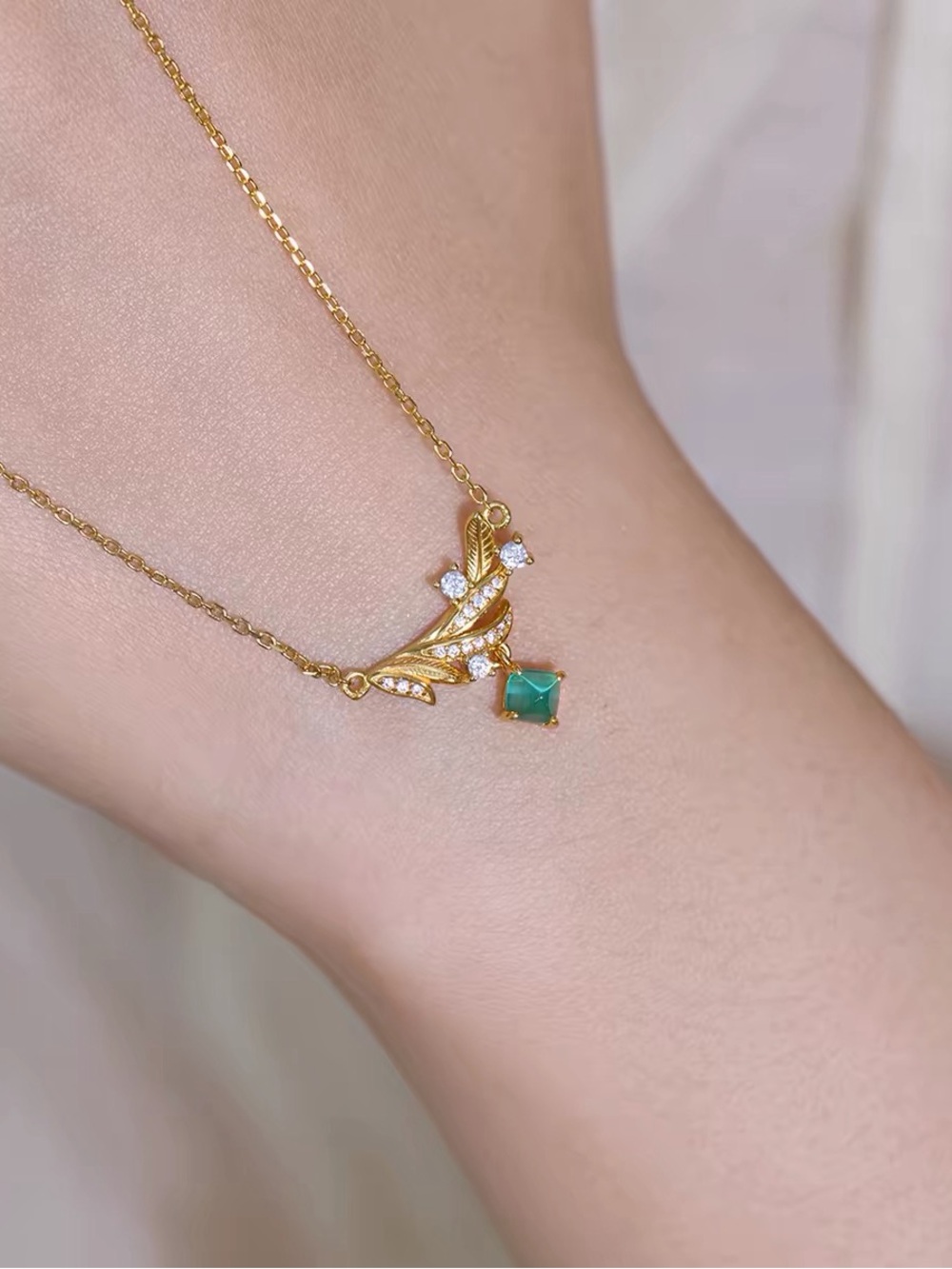 Delicate Gold Necklace with Green Gem and Leaf Accents